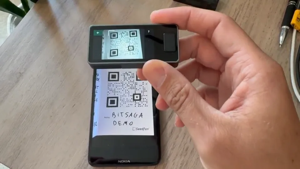 Jade Plus held above a phone showing a QR code marked as a demonstration.