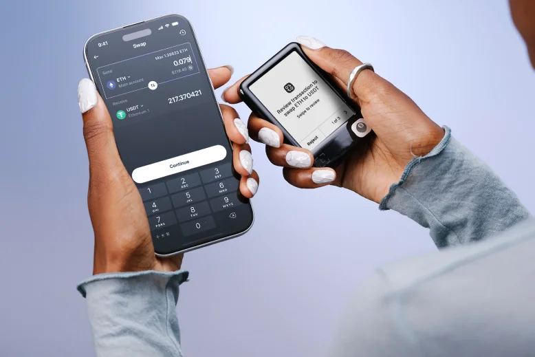 Hands holding a phone with Ledger Wallet and a Ledger Nano Gen5, showing a manufacturer swap-review example.