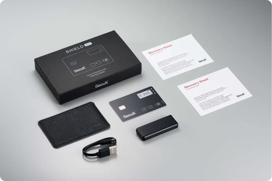 SecuX Shield BIO kit with the card, protective case, charging dock, USB cable, box and two blank paper recovery sheets.
