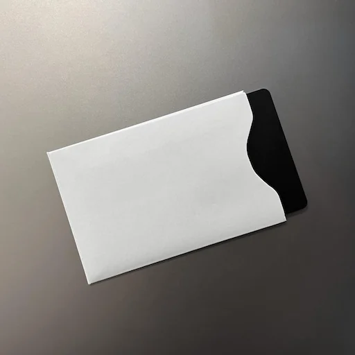 Coinkite’s sleeve demonstration shows a generic black card partly inserted into a pale RF-blocking sleeve.