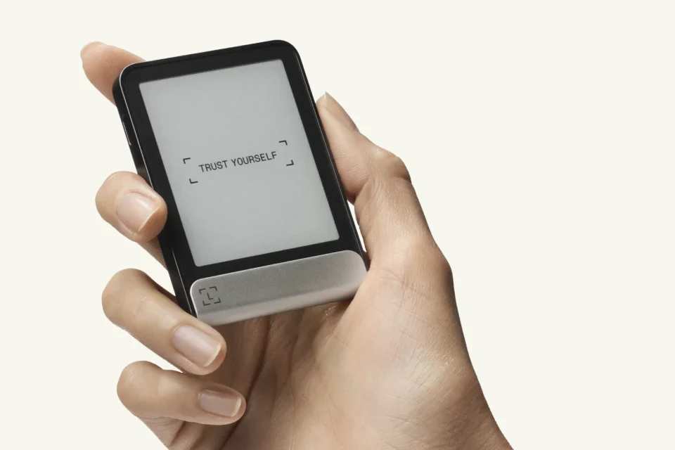 A hand holding a Ledger Flex with its E Ink screen facing the reader.